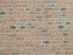 A brick wall with several small drill holes, some filled with mortar, indicating a wall tie survey